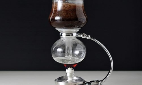 Siphon coffee maker with coffee in top and boiling water in bottom