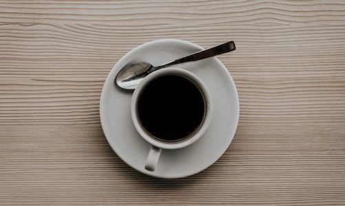 Coffee in a cup on white saucer on wooden table