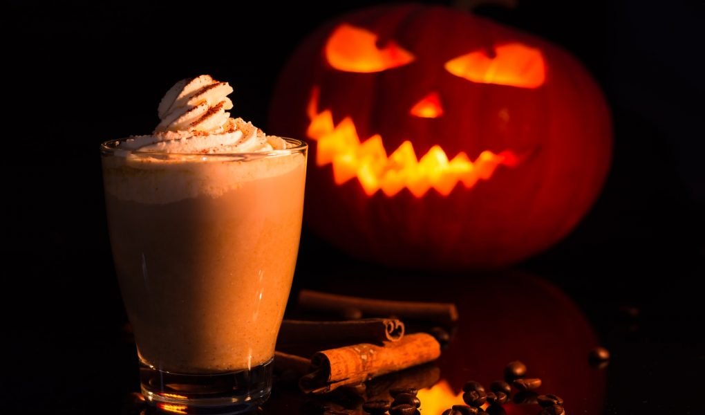 pumpkin spice latte with halloween pumpkin behind